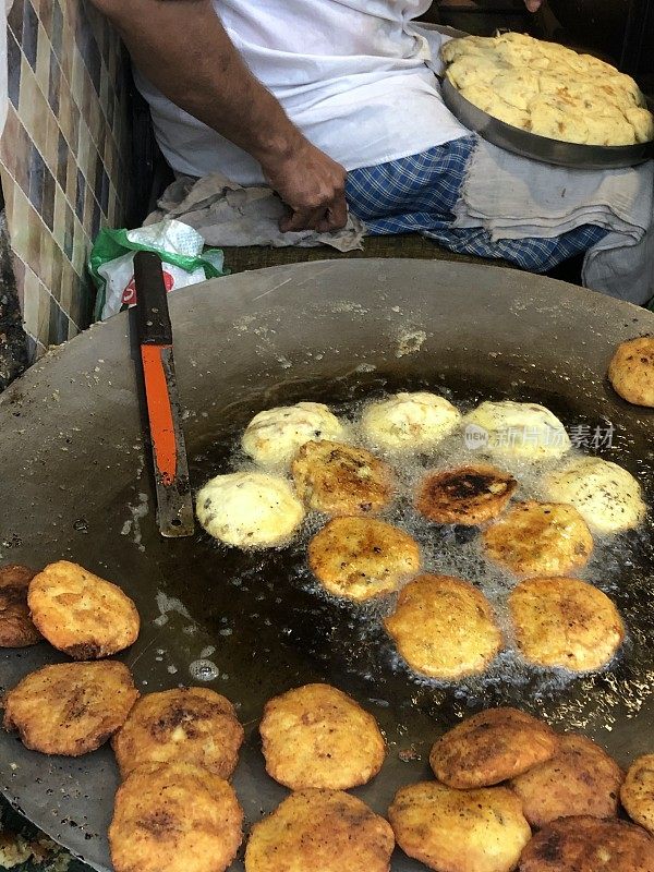 一个男人正在做Aloo tikki / Aloo tikki chaat，在一个大平底锅上用热油油炸，印度街头小吃小贩，印度街头小吃摊，不健康的饮食，新德里，印度，德里肚
